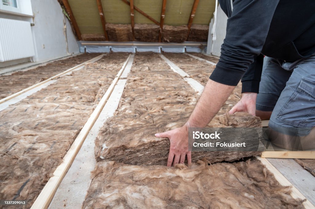 Man insulating the attic with rock wool. Man insulating the attic with rock wool.